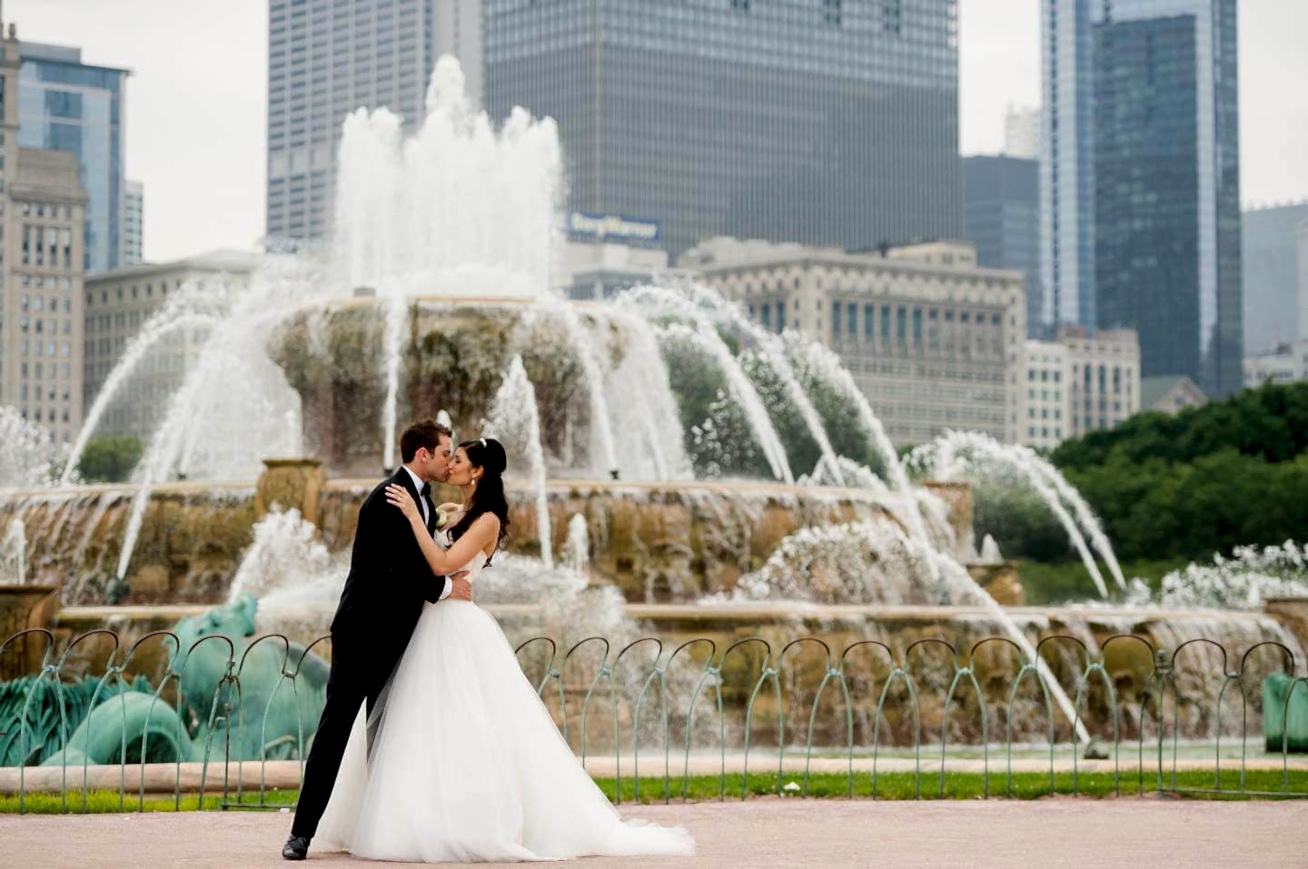 A newlywed couple kissing in front of the fountain